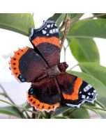 DecoButterfly Atalanta van Wildlife Garden als houten vlinderdecoratie tussen groene bladeren, met donkerbruine vleugels, oranjerode banden en witte vlekken.