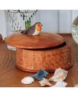 Houten opbergdoos Roodborstje van Wildlife Garden met ronde deksel en houten roodborstje, gefotografeerd op een tafel met schelpen en glazen vaas.