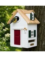 Koolmees bij de ronde invliegopening van de Multiholk New England van Wildlife Garden, een witte houten nestkast en voederhuis met rode deur, groene luiken en licht houten dak, bevestigd aan een boom.