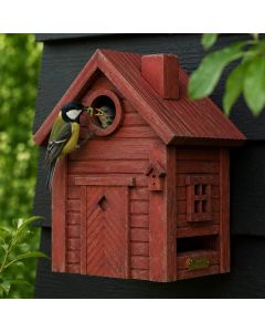 Koolmees voert een jong bij de ronde invliegopening van de Multiholk Red Earth van Wildlife Garden, een rood houten nestkastje tegen een donkere houten wand.