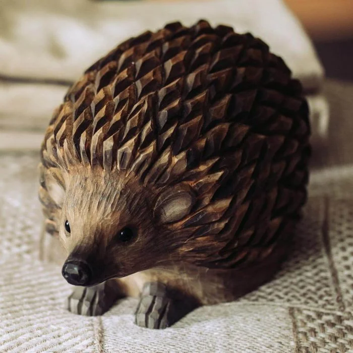 DecoAnimal Egel van Wildlife Garden op een lichtgekleurde stoffen ondergrond, met donkerbruine houten stekels, zwarte ogen, spitse snuit en kleine voorpoten.