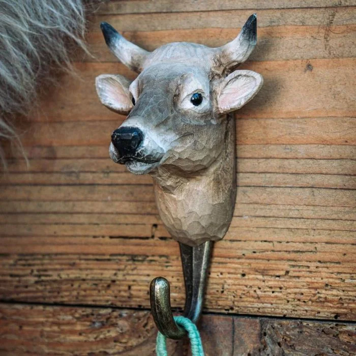 Kledinghaak Koe van Wildlife Garden aan een rustieke houten wand, met bruingrijze koeienkop, zwarte hoornpunten en metalen haak met groen koord.